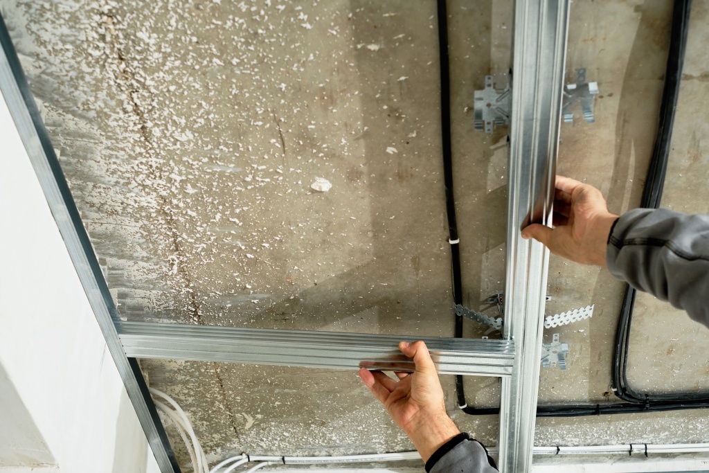 worker-adjusts-a-metal-profile-for-mounting-a-plasterboard-ceiling-frame-close-up-selective-focus-on-the-hands-of-a-specialist-industrial-renovation-and-renovation.jpg